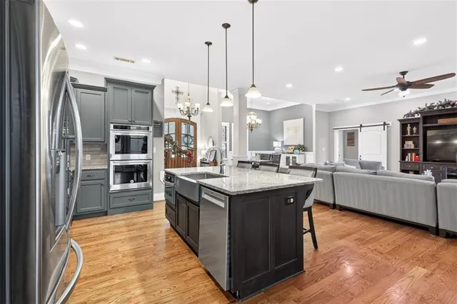 a kitchen with stainless steel appliances granite countertop a kitchen island a stove a refrigerator and a view of living room