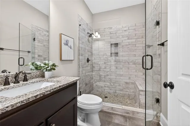 a bathroom with a granite countertop sink toilet and shower