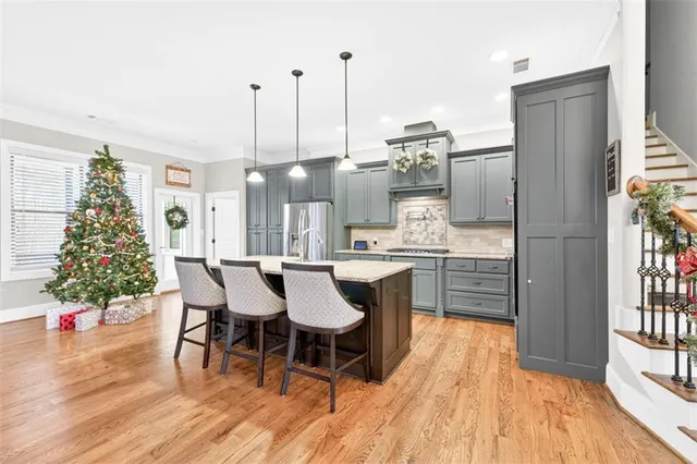 a dining room with stainless steel appliances kitchen island granite countertop a table chairs and a refrigerator