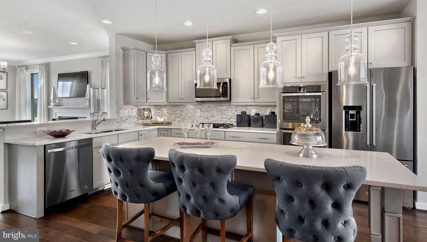 3639 Stone Barn Drive Frederick, MD 21704 - Photo 7 of 21 a kitchen with stainless steel appliances kitchen island granite countertop a table chairs and a refrigerator