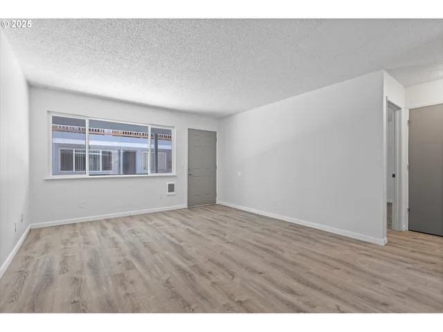 a view of an empty room with wooden floor and windows