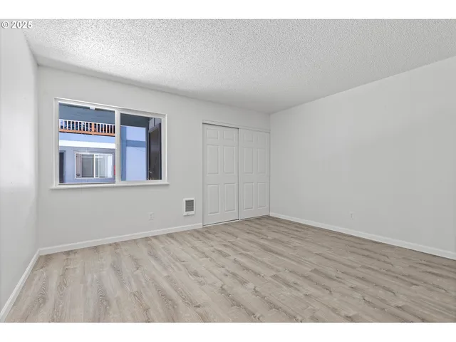 a view of an empty room with wooden floor and windows