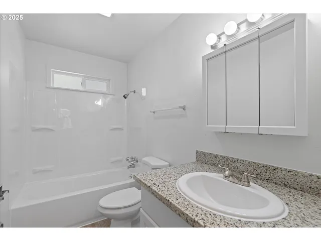 a bathroom with a granite countertop sink toilet mirror and bathtub