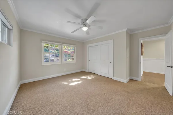 an empty room with windows and ceiling fan