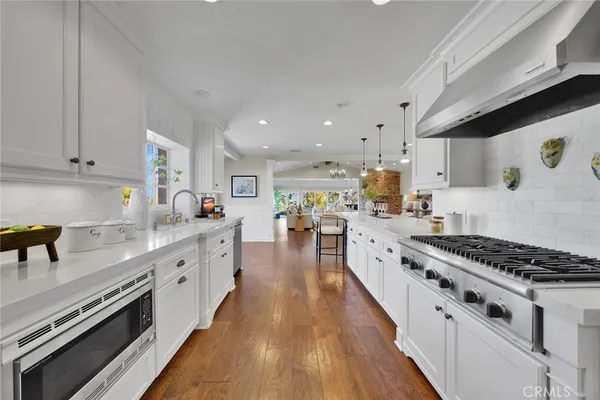 a large kitchen with stainless steel appliances granite countertop a lot of counter space and wooden floors