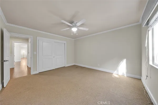 an empty room with chandelier fan and windows