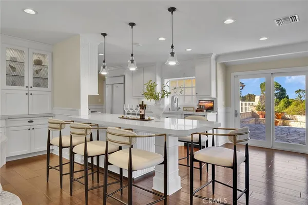 a kitchen with stainless steel appliances kitchen island granite countertop a dining table chairs and white cabinets next to a window