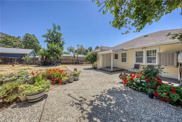 a backyard of a house with large trees and wooden fence