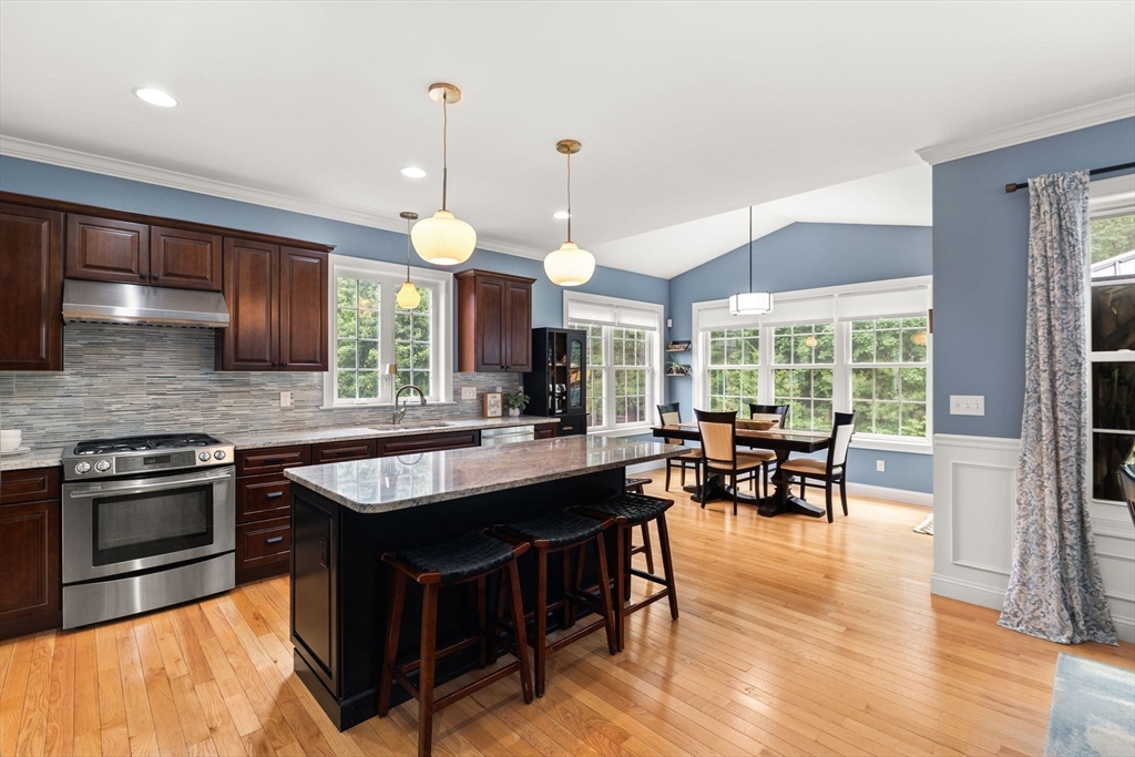 6 Jacoby Way Seekonk, MA 02771 - Photo 12 of 42 a kitchen with stainless steel appliances granite countertop a stove top oven a dining table and chairs with wooden floor