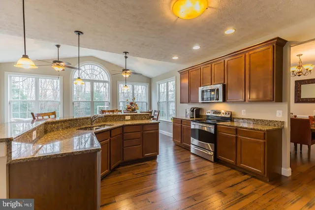 a large kitchen with stainless steel appliances granite countertop a stove and a wooden floors