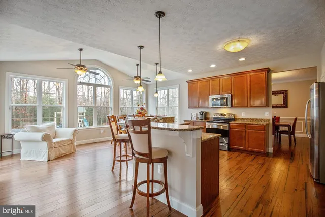 a view of a dining room and livingroom with furniture wooden floor a chandelier