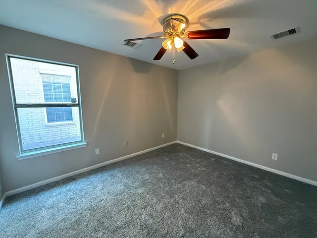 an empty room with a chandelier fan and windows