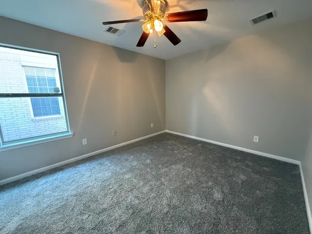 an empty room with windows and fan