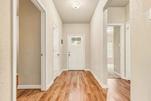 a view of a hallway with wooden floor and a bathroom