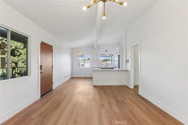an empty room with wooden floor cabinet and windows