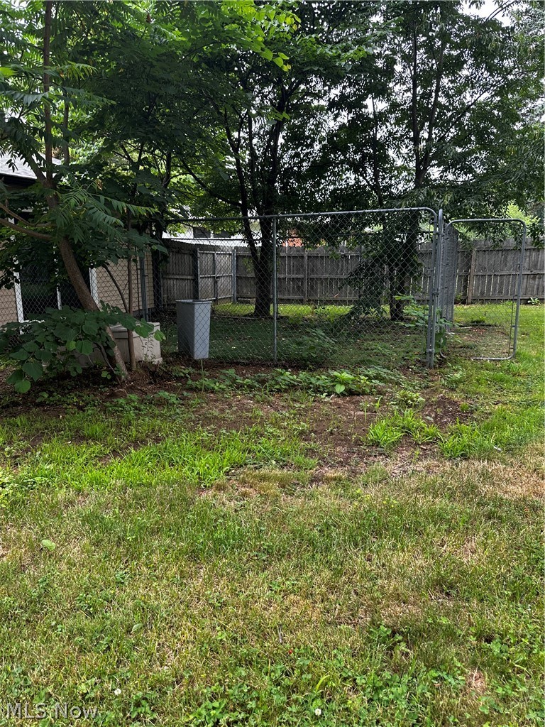 198 Park Road Painesville, OH 44077 - Photo 27 of 31 Fenced backyard featuring mature trees, chain-link fencing, and a wooden privacy fence