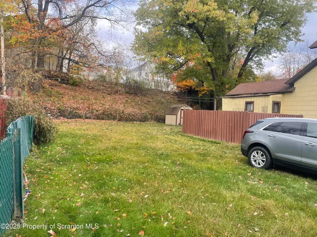 a view of a backyard with table and chairs and a large tree