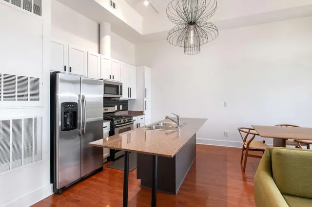 a kitchen with stainless steel appliances a dining table chairs stove refrigerator and microwave