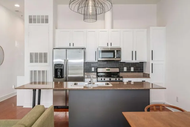 a kitchen with stainless steel appliances granite countertop a sink a stove top oven a chimney and a counter top space