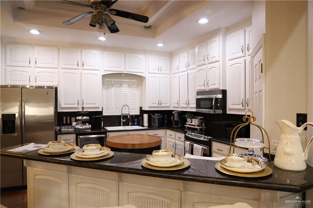 12431 Ware Road Edinburg, TX 78541 - Photo 12 of 37 a kitchen with stainless steel appliances kitchen island granite countertop a sink and chairs
