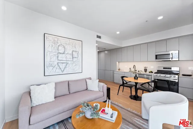 a living room with furniture and kitchen view with wooden floor