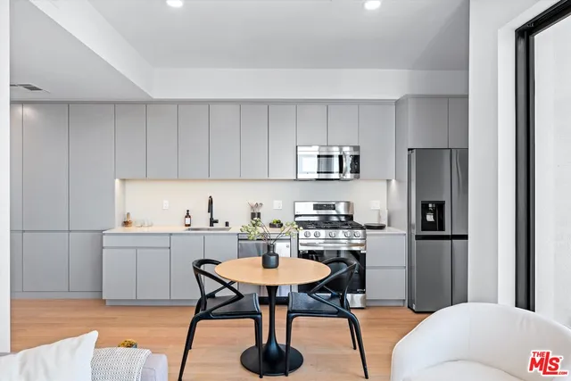 a kitchen with stainless steel appliances a dining table chairs stove refrigerator and cabinets