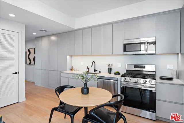 a kitchen with stainless steel appliances a stove a sink cabinets and a dining table