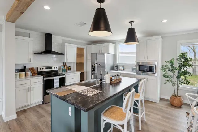 a kitchen with kitchen island granite countertop a sink a center island and stainless steel appliances