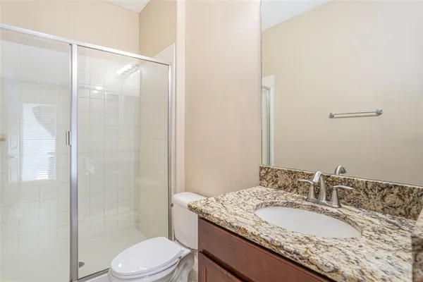 a bathroom with a granite countertop sink toilet mirror and a shower