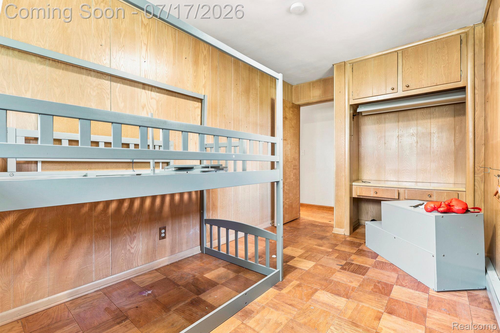 9805 Dolan Road Columbus, MI 48063 - Photo 11 of 39 Wood-paneled room featuring parquet-style flooring, a built-in desk with overhead cabinetry, and an open doorway