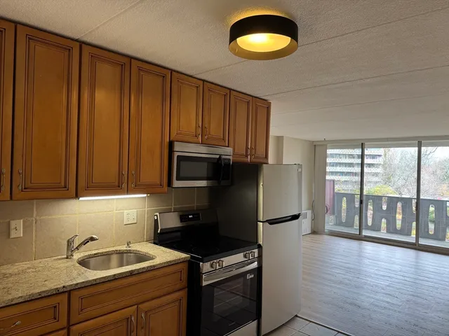 a kitchen with granite countertop a refrigerator stove and sink