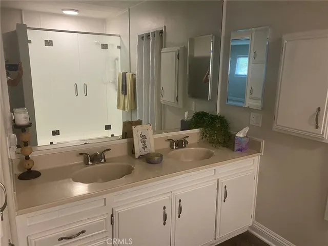 a bathroom with double vanity sink a mirror and shower