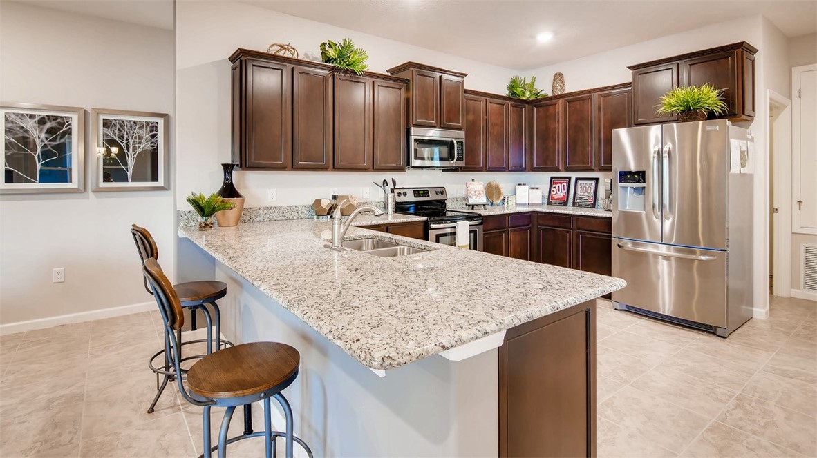 71 52nd Square Vero Beach, FL 32968 - Photo 3 of 16 a kitchen with granite countertop a table chairs refrigerator and microwave