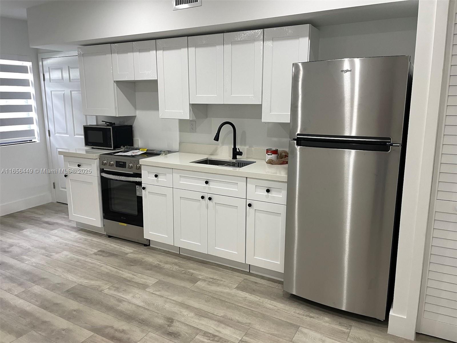 3034 Northwest 14th Avenue Miami, FL 33142 - Photo 2 of 8 a kitchen with a refrigerator sink and cabinets