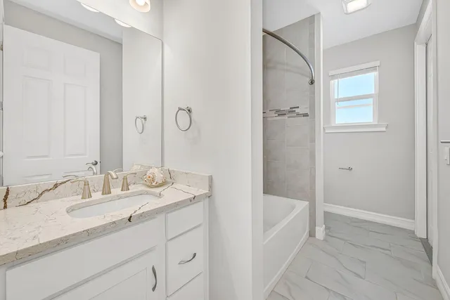 a bathroom with a granite countertop sink a mirror and a bathtub