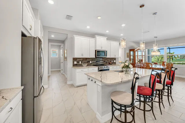 a kitchen with stainless steel appliances kitchen island granite countertop a refrigerator and a dining table