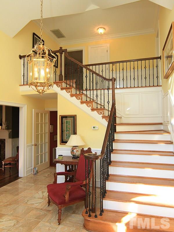 2204 Customs House Court Raleigh, NC 27615 - Photo 3 of 25 The grand foyer with marble flooring, iron pickets, curved staircase welcomes you home. To the left is a formal dining room with vaulted ceiling and gas fireplace. To the right is a huge formal living room with a gas fireplace, moldings & trey ceiling.