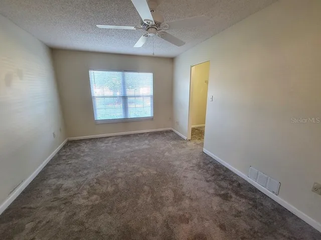 en empty room with windows and chandelier fan