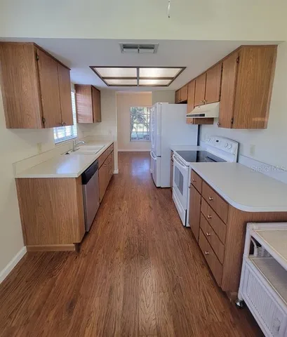 a large kitchen with stainless steel appliances wooden floors and wooden cabinets