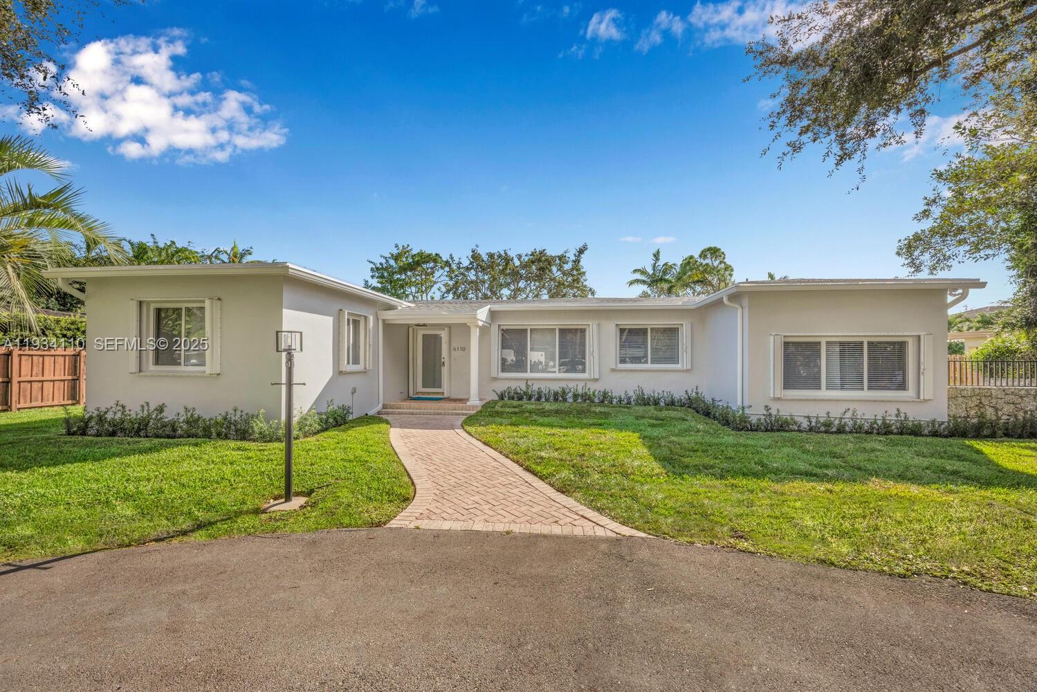a view of a yard in front of a house with plants and large tree
