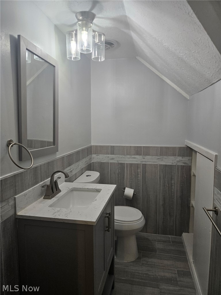 4237 Stonehaven Road South Euclid, OH 44121 - Photo 31 of 35 Bathroom featuring a vanity with a white countertop and integrated sink, wood-look tiled walls, wood-look tiled flooring, and a flush-mount light fixture
