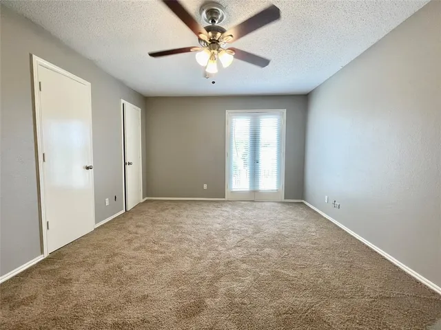 an empty room with a chandelier fan and windows