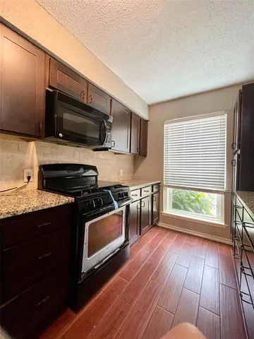a kitchen with stainless steel appliances granite countertop a stove a sink and a microwave