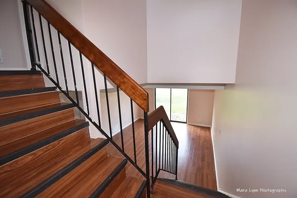 a view of staircase with wooden floor and white walls