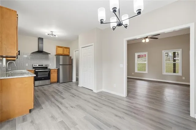 a kitchen with stainless steel appliances granite countertop a stove a sink dishwasher and a refrigerator with wooden floor