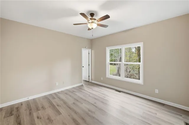 an empty room with wooden floor and ceiling fan