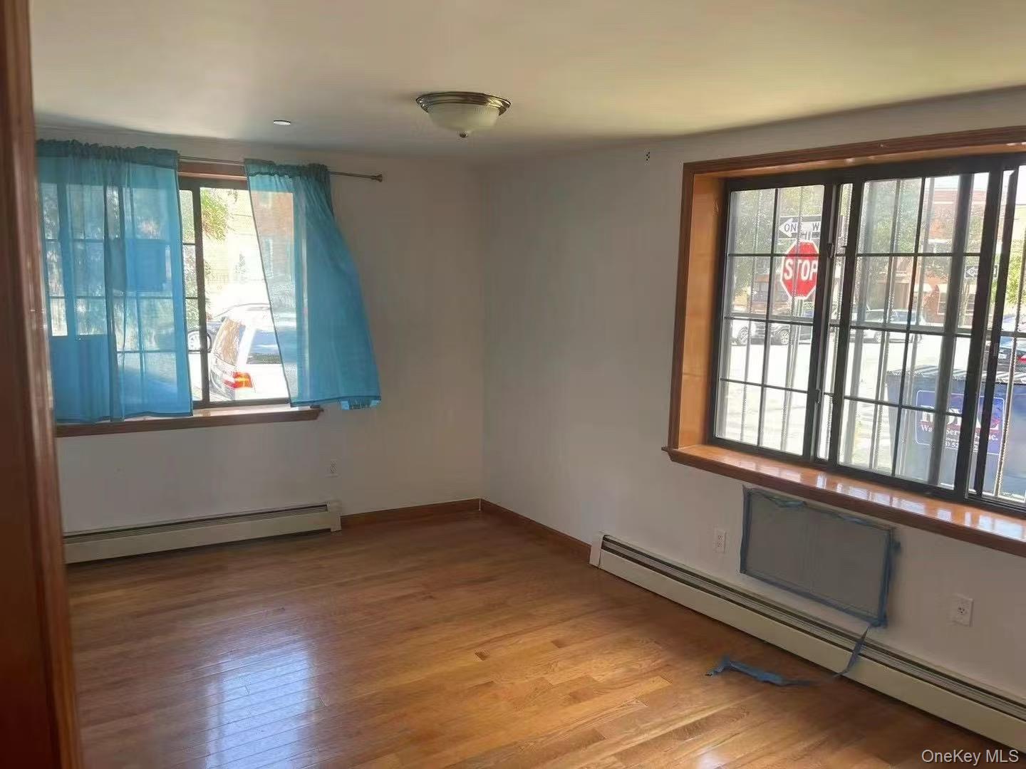 109-15 Westside Avenue, Unit 1A Queens, NY 11368 - Photo 2 of 8 Unfurnished room with a baseboard radiator and wood finished floors