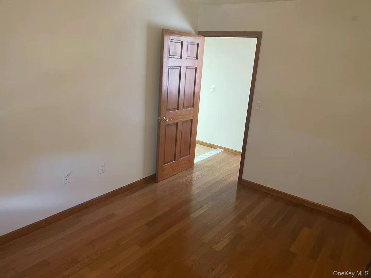 109-15 Westside Avenue, Unit 1A Queens, NY 11368 - Photo 3 of 8 Empty room featuring dark wood finished floors and baseboards