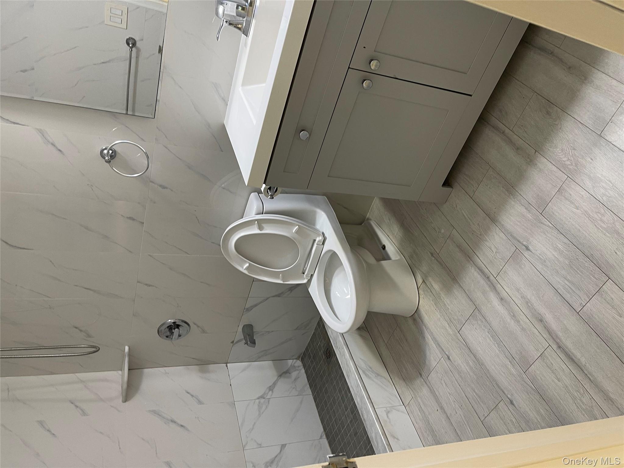 109-15 Westside Avenue, Unit 1A Queens, NY 11368 - Photo 7 of 8 Bathroom featuring tile walls, vanity, a shower stall, and wood tiled floors