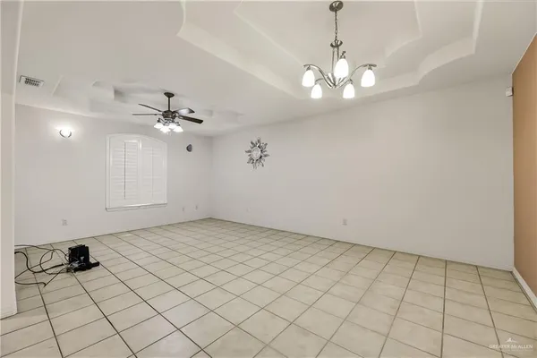 a view of an empty room with a chandelier fan and a rug